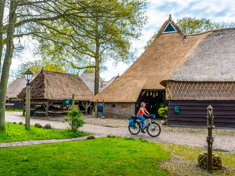 Fietser langs rietgedekte boerderij in Drenthe