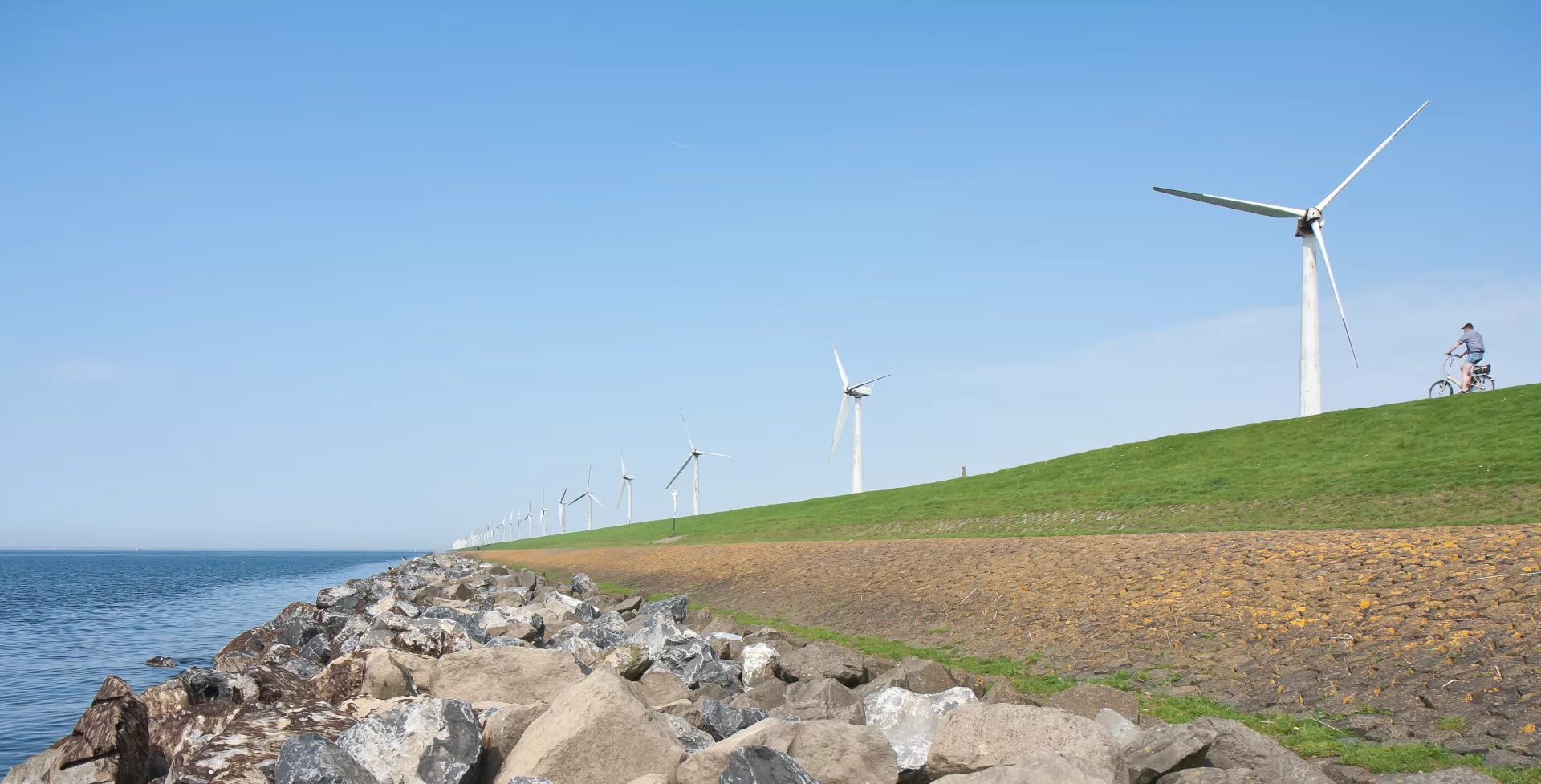 Fietsen over de dijk met windmolens, IJsselmeer, Nederland